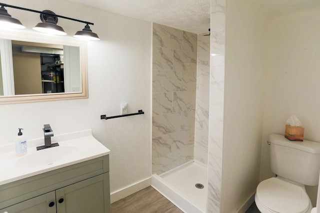 2804 W Crown Ave, Spokane, WA 99205 - bathroom with baseboards, a tile shower, toilet, vanity, and wood finished floors