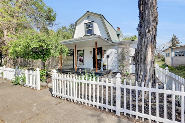 2709 E Sharp Ave, Spokane, WA 99202 - colonial inspired home featuring a porch, a fenced front yard, a chimney, and a gambrel roof