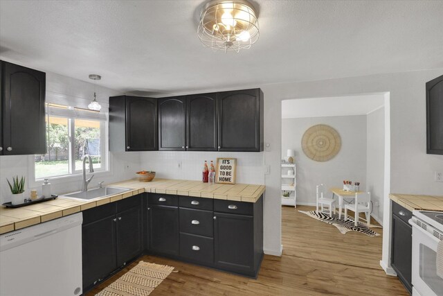 2709 E Sharp Ave, Spokane, WA 99202 - kitchen featuring white appliances, a sink, tasteful backsplash, light wood-type flooring, and tile counters
