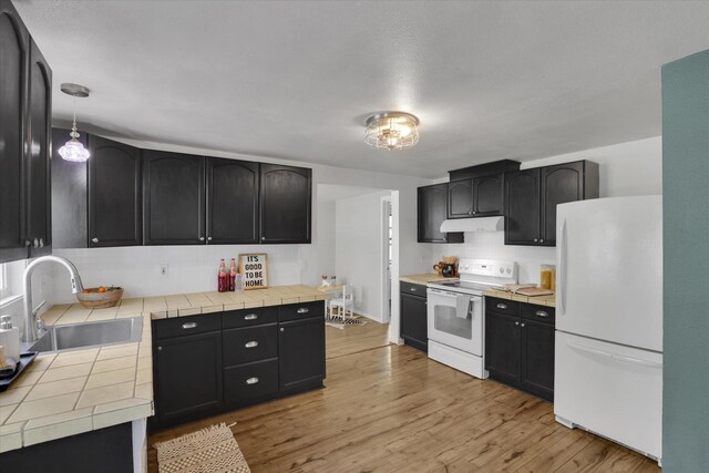 2709 E Sharp Ave, Spokane, WA 99202 - kitchen with white appliances, a sink, light wood-type flooring, and tile counters