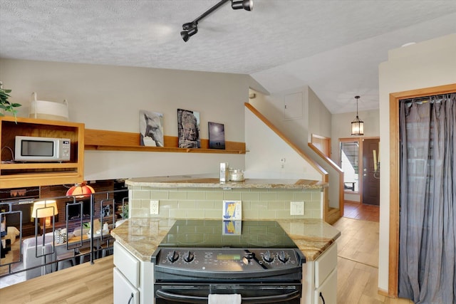 kitchen featuring black electric range oven, white microwave, light wood-style flooring, a textured ceiling, and white cabinets