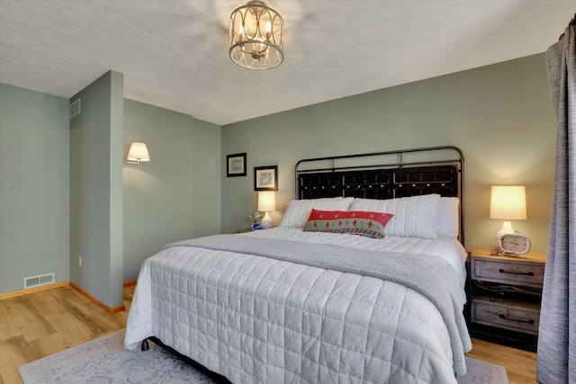 bedroom with wood finished floors, baseboards, and a chandelier
