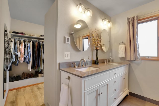 full bath featuring double vanity, baseboards, and a walk in closet