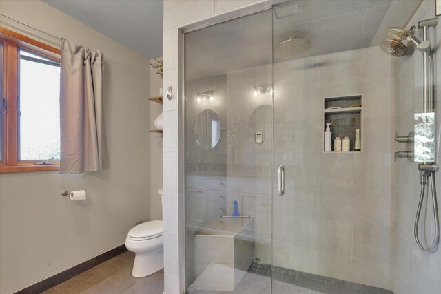 bathroom with toilet, a shower stall, tile patterned floors, and baseboards