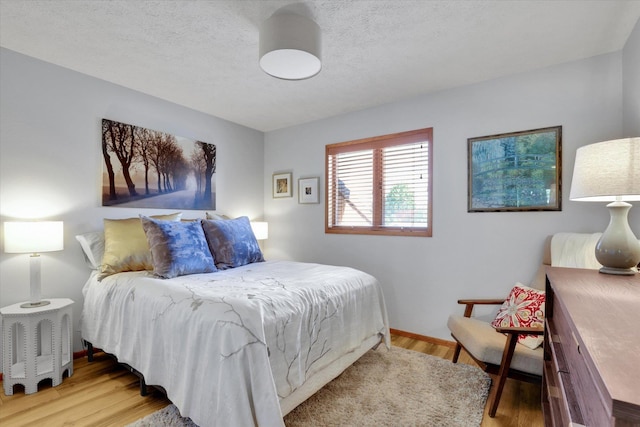 bedroom with light wood-style flooring and a textured ceiling