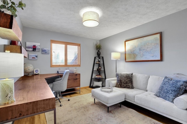 office area with wood finished floors, a textured ceiling, and baseboards