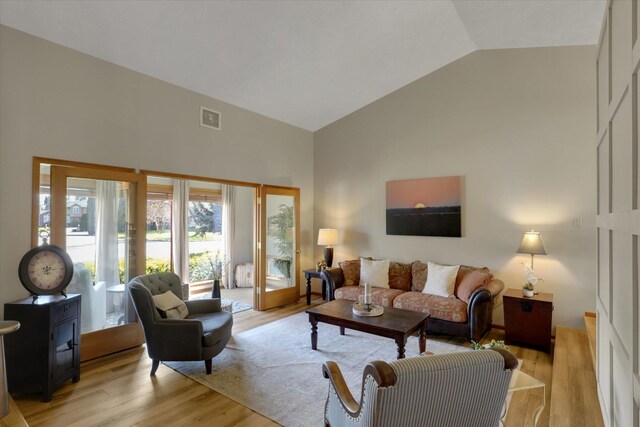 living room featuring high vaulted ceiling and light wood-type flooring