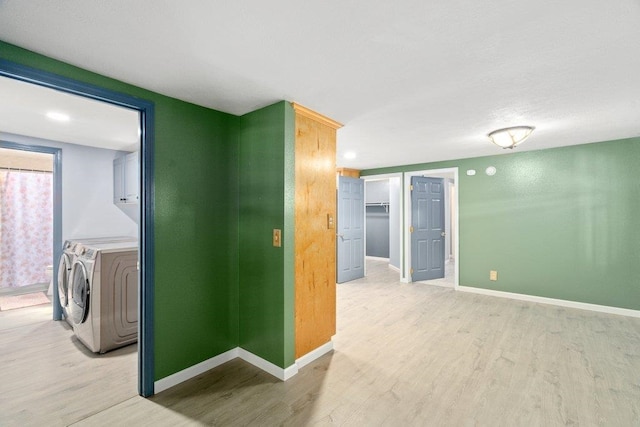 unfurnished room featuring light wood-style floors, washing machine and clothes dryer, and baseboards