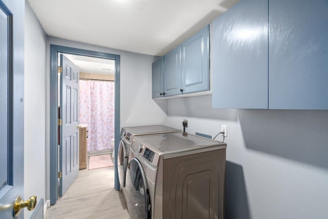 washroom with cabinet space, separate washer and dryer, and light wood-style floors