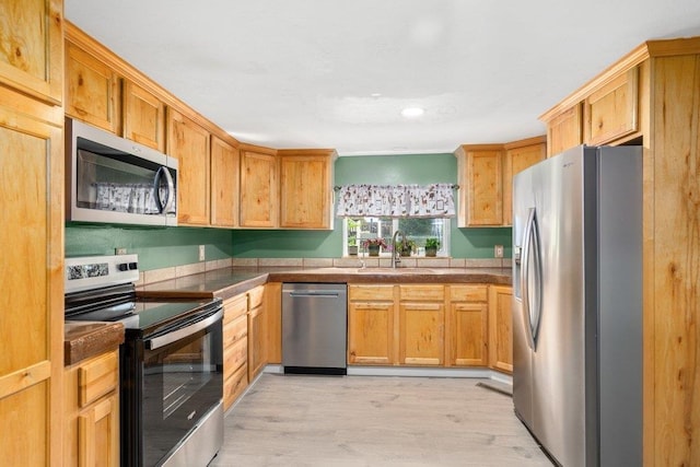 kitchen with appliances with stainless steel finishes, a sink, light wood-type flooring, and recessed lighting