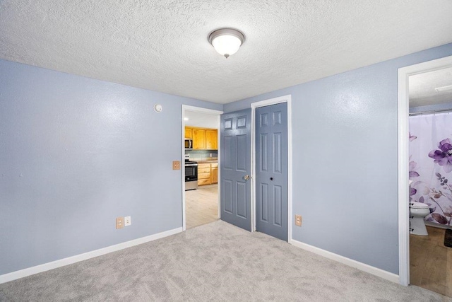 unfurnished bedroom featuring light colored carpet, a textured ceiling, and baseboards