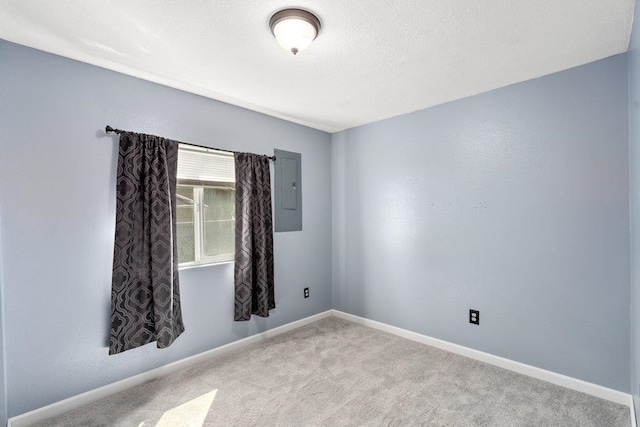carpeted spare room featuring electric panel and baseboards