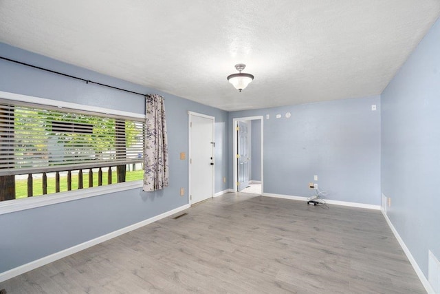 spare room with wood finished floors, baseboards, and a textured ceiling