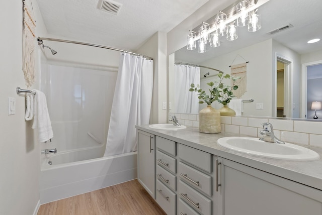 bathroom with wood finished floors, shower / bath combo, double vanity, and backsplash