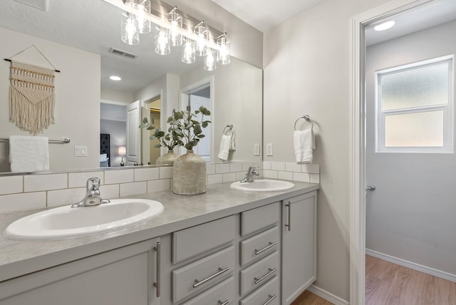 full bath with backsplash, double vanity, wood finished floors, and baseboards
