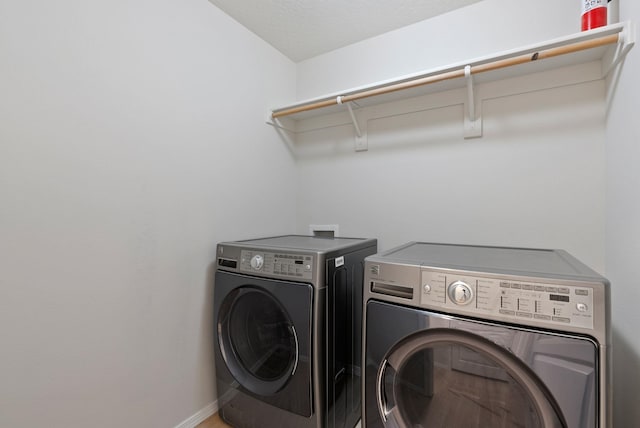 laundry area with washing machine and clothes dryer and baseboards