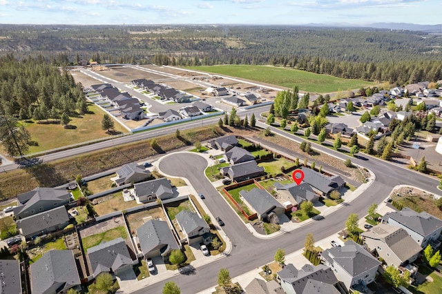 aerial view of property and surrounding area featuring a heavily wooded area and nearby suburban area