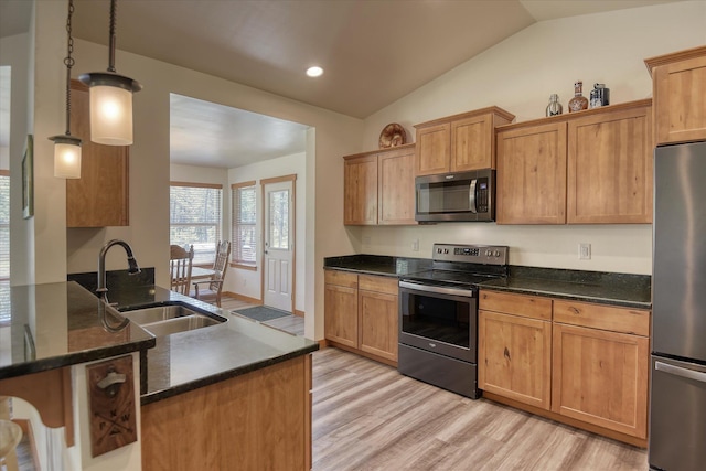 kitchen with appliances with stainless steel finishes, a sink, light wood-type flooring, lofted ceiling, and dark stone countertops
