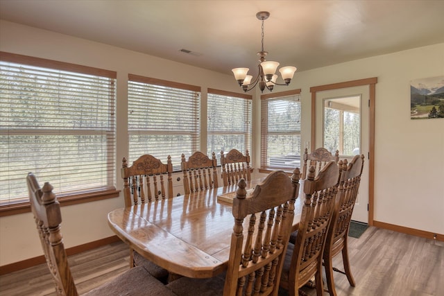 dining area with a chandelier, baseboards, and light wood-style floors