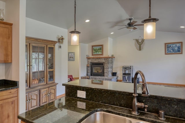 kitchen featuring a sink, a ceiling fan, a stone fireplace, vaulted ceiling, and open floor plan