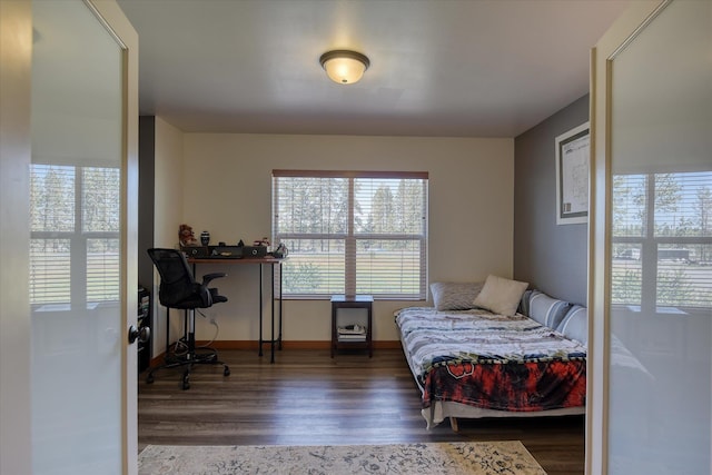 bedroom featuring multiple windows, wood finished floors, baseboards, and a desk