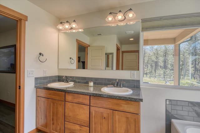 bathroom with double vanity, tasteful backsplash, and a tub