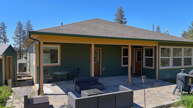 rear view of house featuring central AC unit, a patio area, an outdoor hangout area, and roof with shingles
