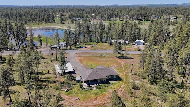 aerial view of property and surrounding area featuring a forest and a large body of water