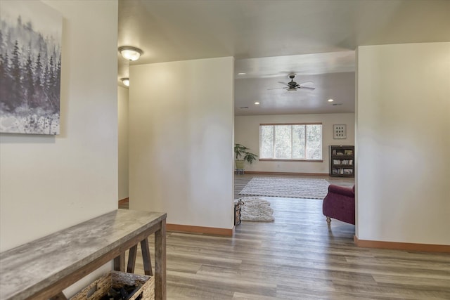 hallway featuring wood finished floors, baseboards, and recessed lighting