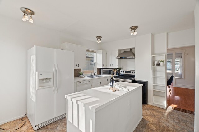 1018 E Broad Ave, Spokane, WA 99207 - kitchen featuring stainless steel appliances, wall chimney range hood, a sink, light countertops, and white cabinets