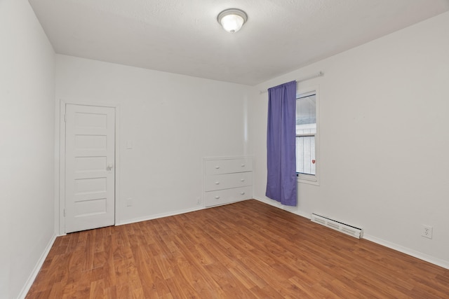 1018 E Broad Ave, Spokane, WA 99207 - empty room with light wood-style floors, baseboards, and a baseboard heating unit