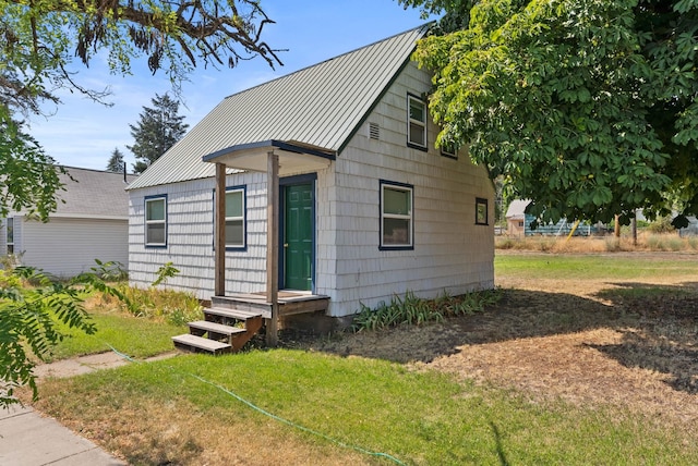 bungalow-style home featuring a front yard, a standing seam roof, and metal roof