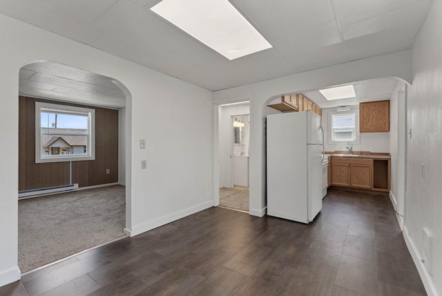 kitchen featuring freestanding refrigerator, a baseboard heating unit, arched walkways, and healthy amount of natural light