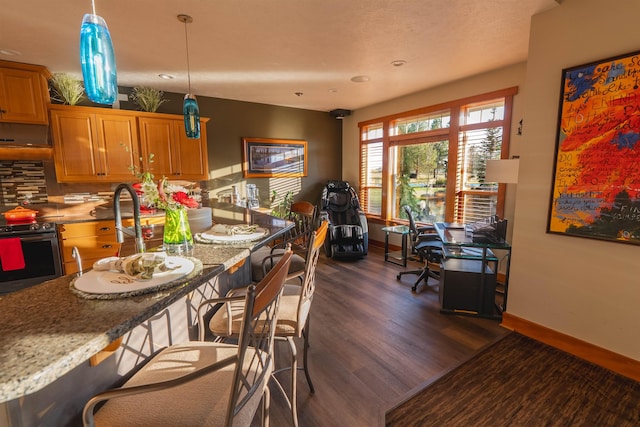 21621 N Lang Ln, Chattaroy, WA 99003 - kitchen with electric stove, dark wood-style flooring, a kitchen bar, under cabinet range hood, and baseboards