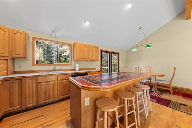 14512 N Dartford Dr, Spokane, WA 99208 - kitchen featuring tile counters, a sink, a breakfast bar, vaulted ceiling, and light wood-style flooring