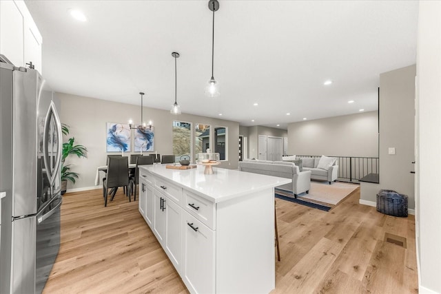 4243 W Tolliver Ct, Spokane, WA 99208 - kitchen featuring freestanding refrigerator, white cabinetry, light wood-type flooring, a kitchen island, and baseboards