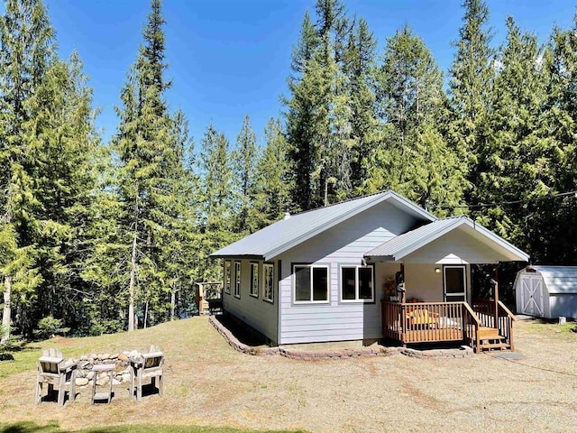 view of front facade with a shed, a fire pit, an outbuilding, a wooden deck, and a front lawn