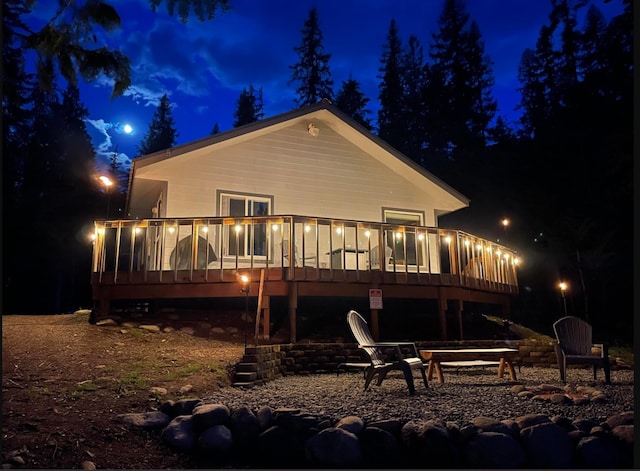 back of house at twilight featuring a deck and a patio area