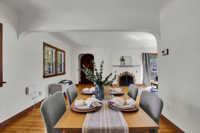 1308 W 11th Ave, Spokane, WA 99204 - dining room featuring arched walkways, wood finished floors, baseboards, and a fireplace