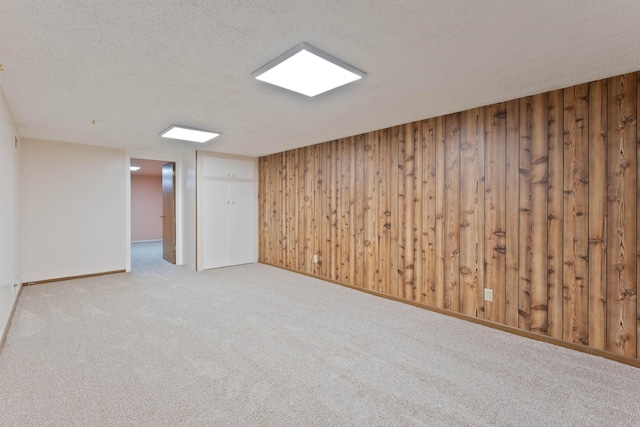 finished basement with carpet flooring, a textured ceiling, wooden walls, and baseboards
