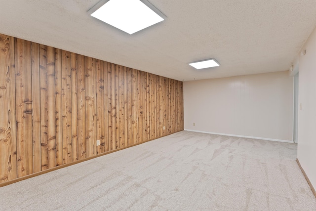 carpeted empty room with wood walls and a textured ceiling