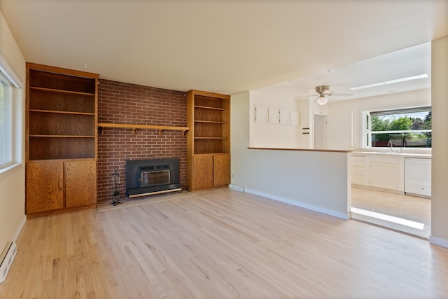 unfurnished living room with light wood finished floors, built in shelves, baseboards, a brick fireplace, and ceiling fan