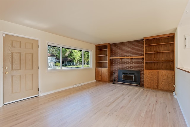 unfurnished living room featuring light wood finished floors, built in shelves, baseboards, and a fireplace