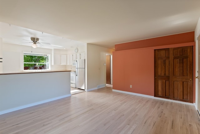 unfurnished living room with light wood-style flooring, a ceiling fan, and baseboards
