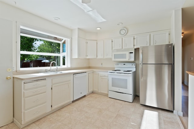 kitchen with white appliances, light countertops, a sink, white cabinetry, and recessed lighting