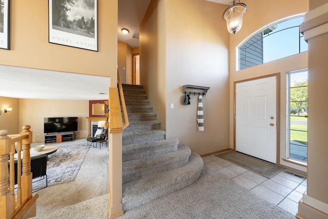 foyer with tile patterned floors, stairway, and a towering ceiling