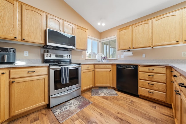 kitchen with stainless steel appliances, light brown cabinets, lofted ceiling, and light wood-style floors