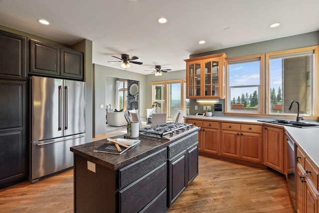 18707 E Terrapin Ln, Otis Orchards, WA 99027 - kitchen with stainless steel appliances, a sink, light wood-type flooring, glass insert cabinets, and a ceiling fan