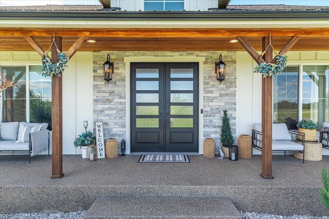 15921 W Four Mound Rd, Nine Mile Falls, WA 99026 - doorway to property featuring stone siding, board and batten siding, french doors, and a porch