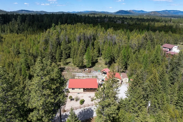 bird's eye view of a heavily wooded area and a mountain backdrop